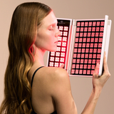 Woman holding the illuminated Alora hinged LED panel near her face